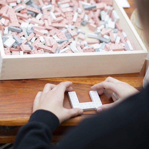 Ein Kind legt KINGSTONES Bausteine zusammen, eine große KINGSTONES Bausteinkiste aus Holz ist zu sehen