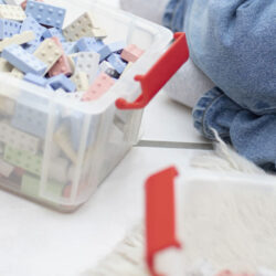 Plasteboxen mit KINGSTONES Steine auf dem Boden, im Anschnitt ist ein Kind zu sehen