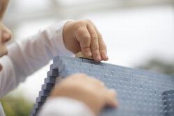 Ein Kleinkind setzt auf dem Dachfirst Hauses aus KINGSTONES einen Stein